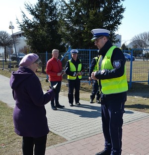 seniorka czyta ulotkę, którą otrzymała od policjanta