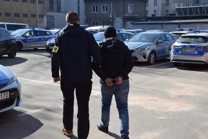 na parkingu komendy, nieumundurowany policjant prowadzi zatrzymanego