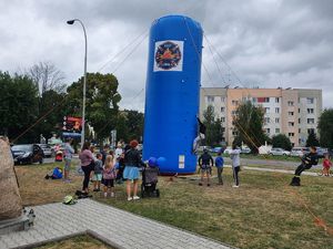 Dzieci spinające się na dmuchaną ścianę wspinaczkową, obok stoją dorośli oraz dzieci