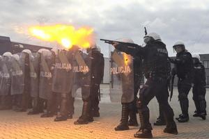 policjant strzelający ze strzelby gładkolufowej