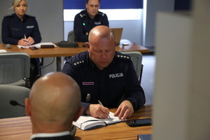 policjanci na sali odpraw siedzący na spotkaniu roboczym w sprawie Odblaskowej szkoły