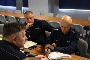 policjanci na sali odpraw siedzący na spotkaniu roboczym w sprawie Odblaskowej szkoły