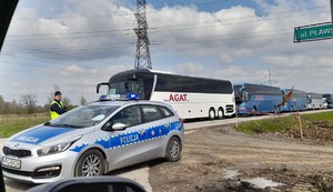 KPP Oświęcim. Marsz Żywych 2023  Policjant stoi przy radiowozie w tle autokary