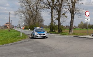 KPP Oświęcim. Marsz Żywych 2023  Radiowóz jedzie ulicą wzdłuż  ogrodzenia Birkenau