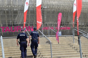 dwóch umundurowanych policjantów wchodzących po schodach przed obiektem Tauron Arena