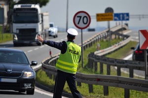 Policjant podczas zatrzymywania pojazdu do kontroli, wskazujący kierwocy miejce do zatrzymania samochodu