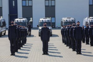 6. Ślubujący policjanci ustawieni w 3 rzędach, w tle policyjne radiowozy