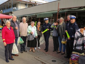 Policjantka i policjant stoją wraz osobami z elementami odblaskowymi