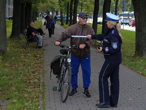 Policjantka wręcza rowerzyście element odblaskowy