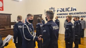 Komendant wręcza akt mianowania i gratuluje nowemu policjantowi