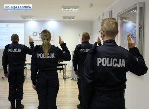 policjanci skierowani w stronę wyświetlonego slajdu ślubują mając podniesione prawe ręce