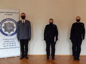 na tle banera jednostki stoi komendant i nowi policjanci