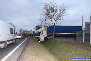 zestaw ciężarowy w rowie przy drodze, na jezdni obok ciąg pojazdów