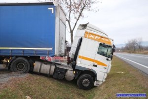 ciągnik siodłowy koloru białego z niebieską naczepą w rowie