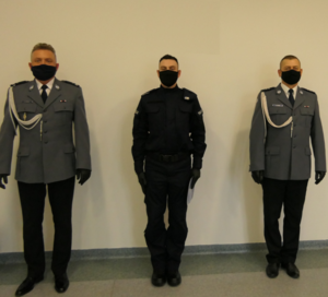 Trzech policjantów stoi przy ścianie