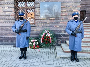 wieńce złożone pod tablicą patrona i policjanci z warty honorowej