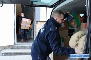 policjanci i pracownicy policji pakują zebrane dary do samochodu