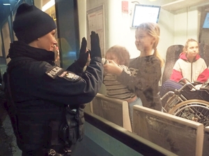 policjantka trzyma ręce na szybie, gdzie po drugiej stronie są dzieci