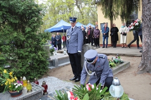 komendant składa wieniec na gronie, pozostali policjanci stoją w tle