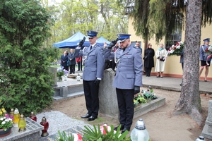 komendant i policjant oddają honor przy gronie , w tle widać innych uczestników