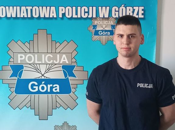 policjant stojący na tle planszy POLICJA GÓRA