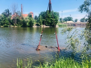 wyciąganie samochodu osobowego z wody na barkę przy pomocy dźwigu