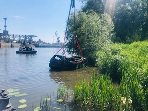 wyciąganie samochodu osobowego z wody na barkę przy pomocy dźwigu