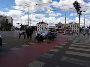 radiowóz blokujący ruch na skrzyżowania, obok ludzie próbujący wydostać kaczkę spod auta,