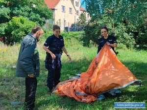 Policjantki rozkładają namiot, obok stoi mężczyzna