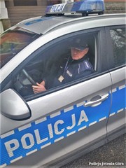 Zdjęcie przedstawia umundurowanego policjanta w radiowozie