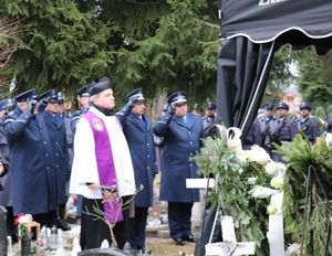 na pierwszym planie stoi ksiądz za nim policjanci w mundurach galowych