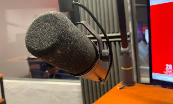 Ma zdjęciu mikrofon w studiu radiowym.