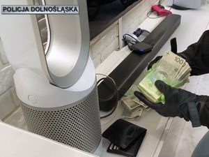 W pomieszczeniu ręce w rękawiczkach trzymające plik banknotów