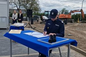 Na zdjęciu Komendant Wojewódzki Policji we Wrocławiu nadinsp. Dariusz Wesołowski podpisujący akt erekcyjny w tle plac budowy z maszynami budowlanymi.