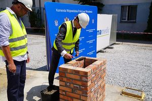 Prezes firmy Climatic  w towarzystwie przedstawiciela firmy budowlanej podczas wmurowania tuby - kapsuły czasu.