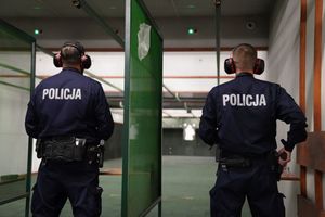 Dwaj policjanci przygotowują się do oddania strzału do tarczy na strzelnicy.