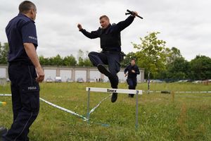 Policjanci skaczą przez płotki.