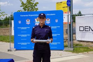 Policjantka trzyma pamiątkową tubę z podpisanym aktem erekcyjnym.