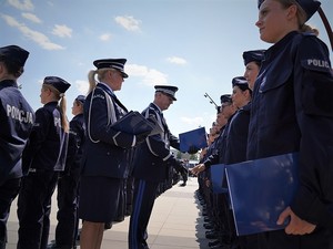 Komendant Wojewódzki Policji we Wrocławiu nadinspektor Dariusz Wesołowski przekazuje dyplom nowo przyjętemu policjantowi stojącemu w szeregu podczas uroczystości ślubowania.
