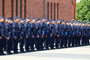 Nowo przyjęci policjanci stojący w dwuszeregu podczas uroczystego apelu.