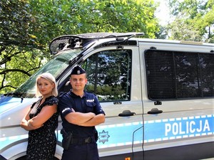 Kobieta z umundurowanym policjantem na tle oznakowanego radiowozu