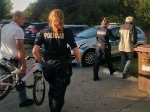 Policjantki z zatrzymanym mężczyzną kierują się w stronę radiowozu