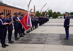 Komendant Wojewódzki Policji we Wrocławiu nadinspektor Dariusz Wesołowski oddaje honory sztandarowi. W tle poczet sztandarowy.