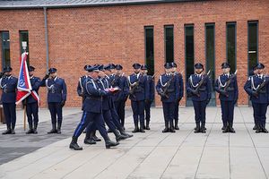 Trzej policjanci niosą złożoną flagę Polski.