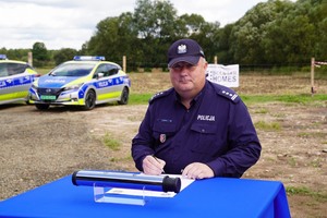 Komendant  Miejski Policji w Jeleniej Górze inspektor Leszek Zagórski siedzący przy stole podpisuje dokument.