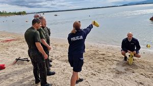 Policjantka pokazuje żołnierzom jak prawidłowo używać rzutki ratowniczej.