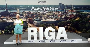 Kobieta w letnim stroju stojąca przy dużym napisie RIGA