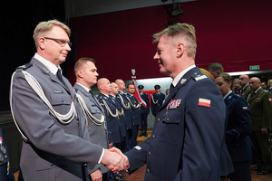 Nadinspektor Dariusz Wesołowski gratuluje policjantowi.W tle pozostali odznaczeni policjanci.