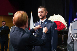 Przedstawicielka Wojewody dolnośląskiego przypina medal policjantowi.