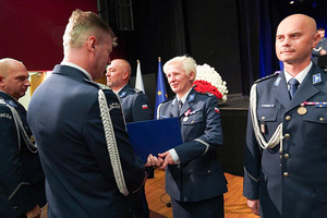 Komendant Wojewódzki Policji we Wrocławiu nadinspektor Dariusz Wesołowski gratuluje odznaczonej policjantce stojącej w szeregu.